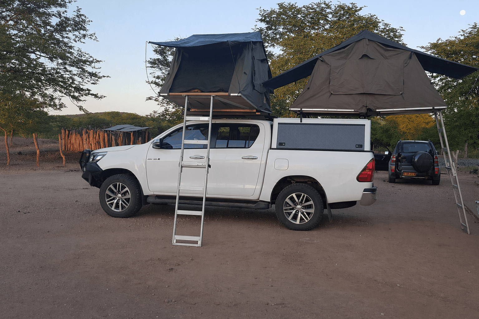 A fully-equipped Toyota Hilux double-cab 4x4 with rooftop tents at a Southern African bush camp