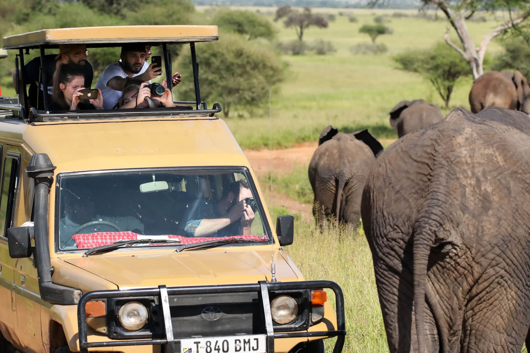 4x4 vehicles driving in convoy through African wilderness with mountains in the background