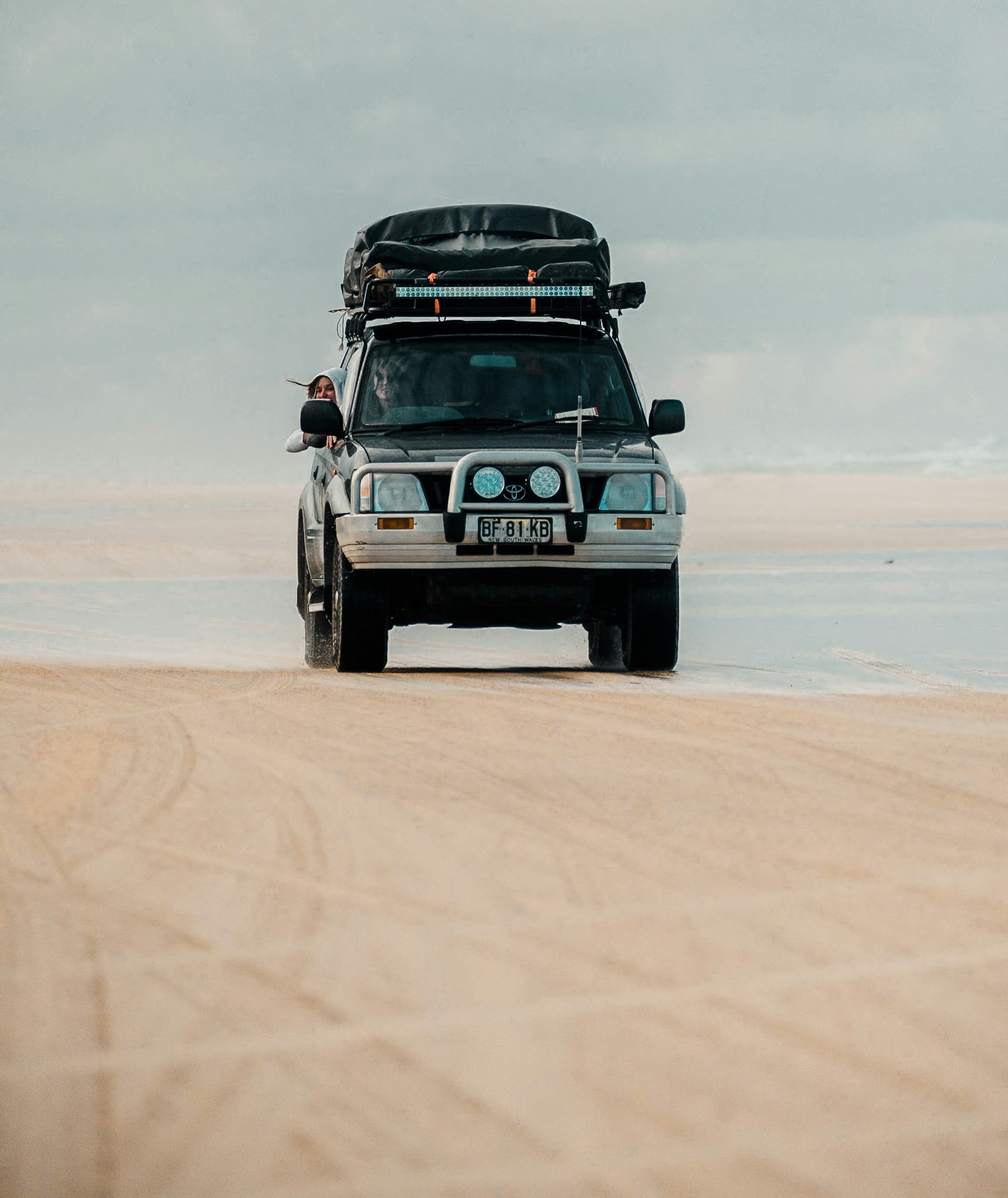 Toyota 4x4 vehicle with rooftop tent driving across sandy terrain in Namibia