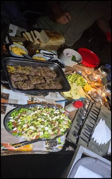 Campfire meal with grilled meats and fresh salads