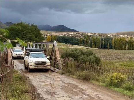 Vehicles at mountain gate approach with pastoral landscape