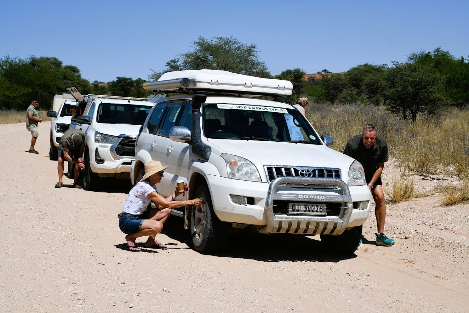 4x4-Konvoi hält auf staubiger Straße mit Wilde-Kalahari-Tour-Fahrzeugen