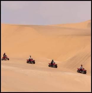 Groep op quads rijdt over enorme zandduinen