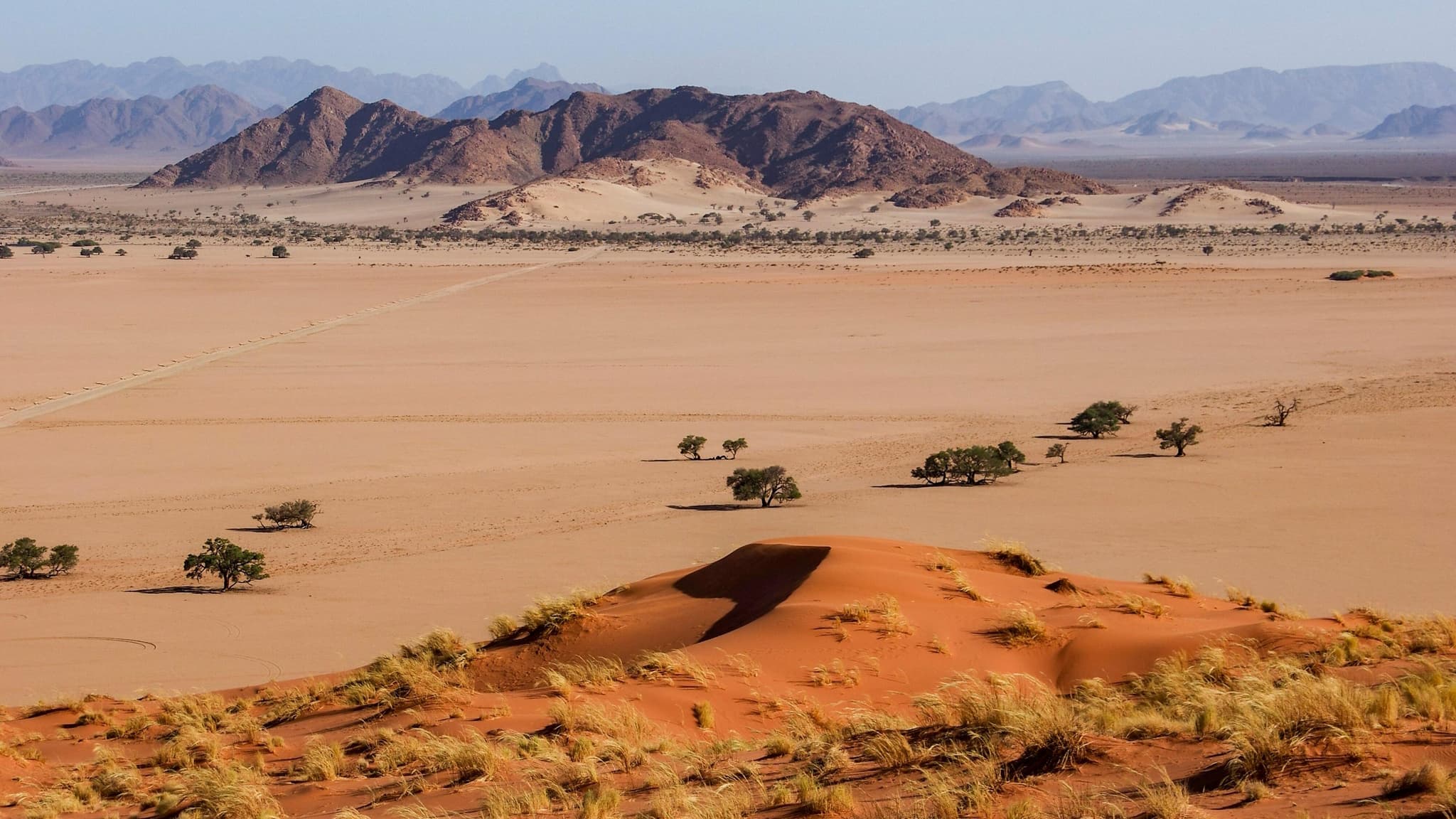 4x4 convoy driving through a dramatic rocky gorge with shallow river crossing in Namibia's Kaokoveld
