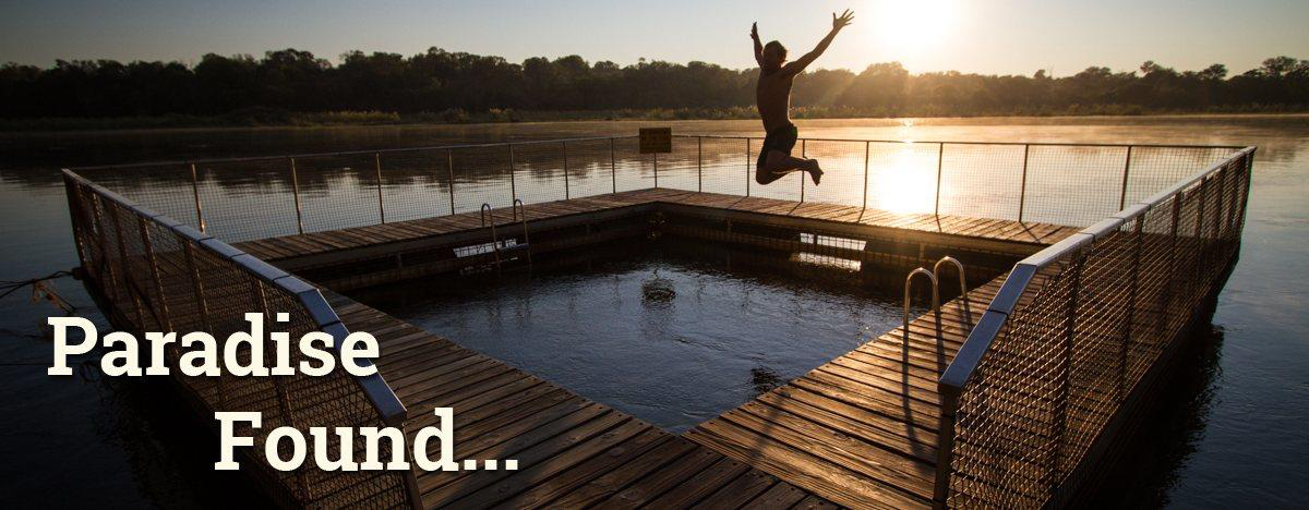 Person leaping into a floating deck swimming pool on the Kavango River at sunrise at Ngepi Camp