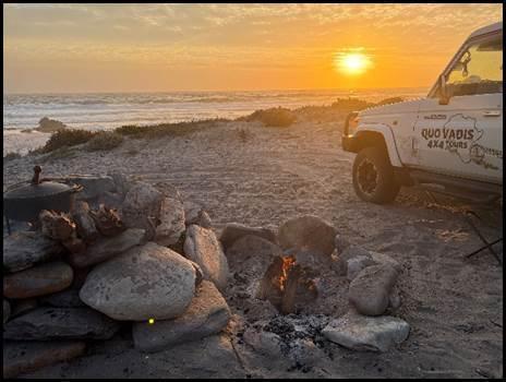4x4 vehicle at sunset on the West Coast beach with campfire