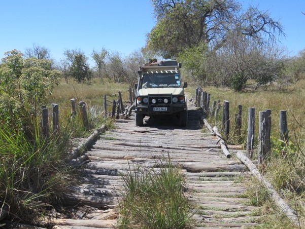 4x4 Land Cruiser überquert eine rustikale Holzbrücke im afrikanischen Busch