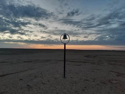 Einsame Glocke als Silhouette vor dem Sonnenuntergangshimmel über der Verneukpan-Salzpfanne