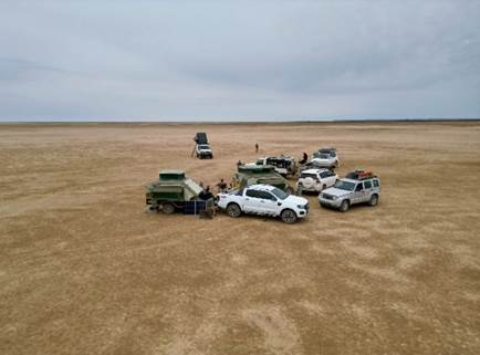Luftaufnahme von 4x4-Fahrzeugen und Camp-Aufbau auf der weiten Verneukpan-Salzpfanne