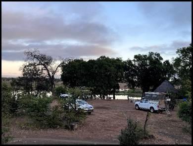 Kampeerplaats met 4x4-voertuigen onder grote bomen bij Chipinda Pools