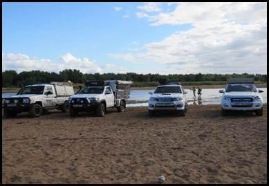 Konvooi van 4x4-voertuigen op zandig terrein bij de rivieroversteek