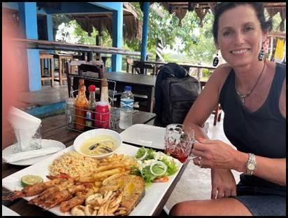Gast geniet van een heerlijke zeevruchtenschotel in het strandrestaurant