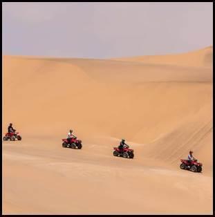 Groep op quads rijdt over enorme zandduinen